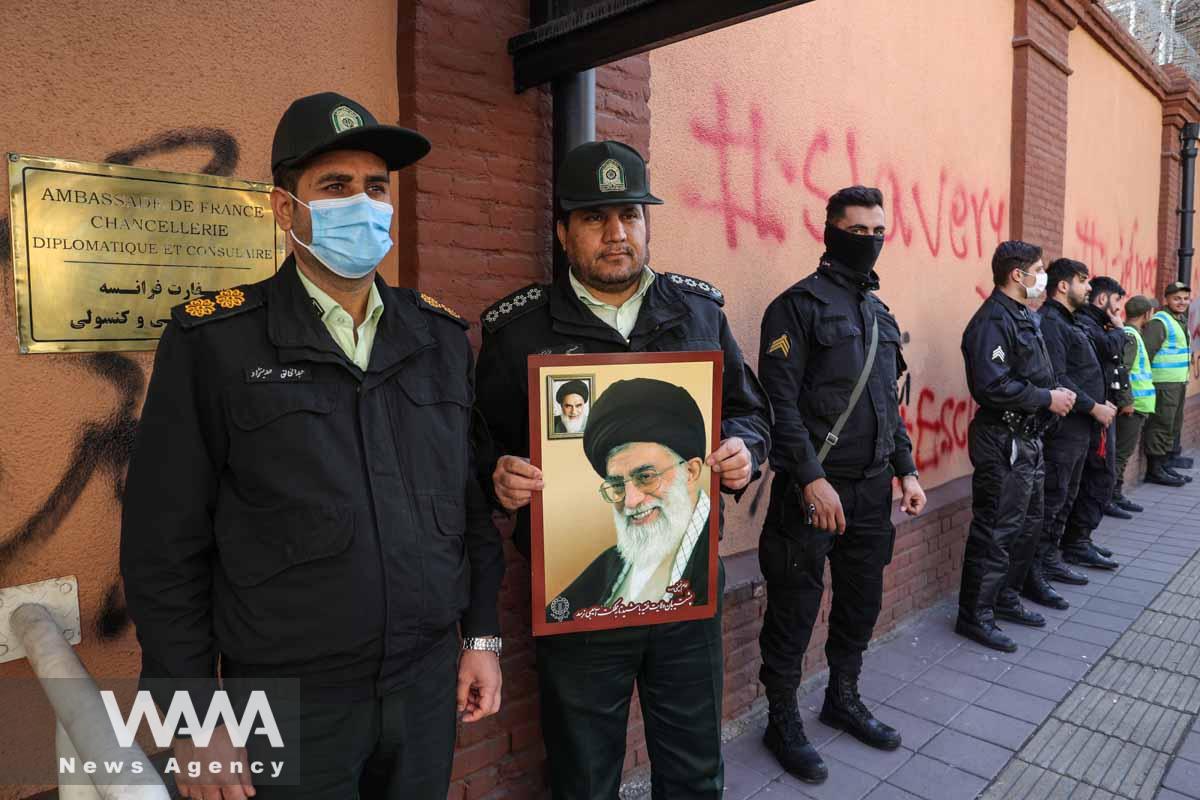 A Police member holds a picture of Ayatollah Ali Khamenei, during a protest to condemn the French magazine Charlie Hebdo for republishing cartoons insulting Iran's Supreme Leader Ayatollah Ali Khamenei, in front of the French Embassy in Tehran, Iran, January 8, 2023. Majid Asgaripour/WANA (West Asia News Agency)