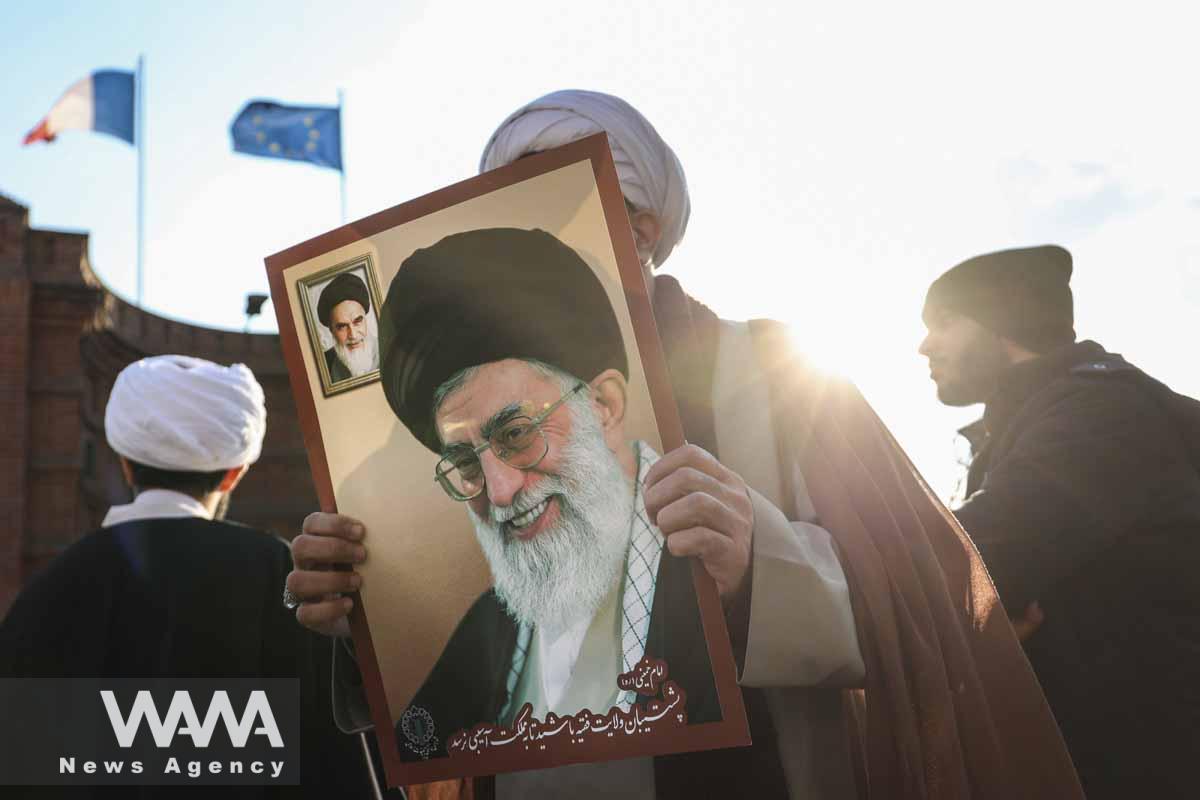 An Iranian cleric holds a picture of Ayatollah Ali Khamenei, during a protest to condemn the French magazine Charlie Hebdo for republishing cartoons insulting Iran's Supreme Leader Ayatollah Ali Khamenei, in front of the French Embassy in Tehran, Iran, January 8, 2023. Majid Asgaripour/WANA (West Asia News Agency)