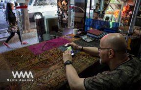 A glass seller in his shop checking election news via smartphone / WANA News Agency