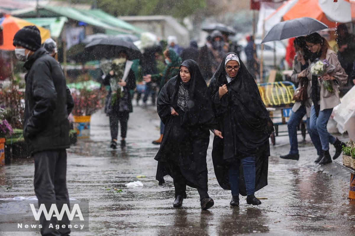 Iranian women walk through rain in a flower market, ahead of Nowruz, the Iranian New Year, in Tehran, Iran March 16, 2023. Majid Asgaripour/WANA (West Asia News Agency)