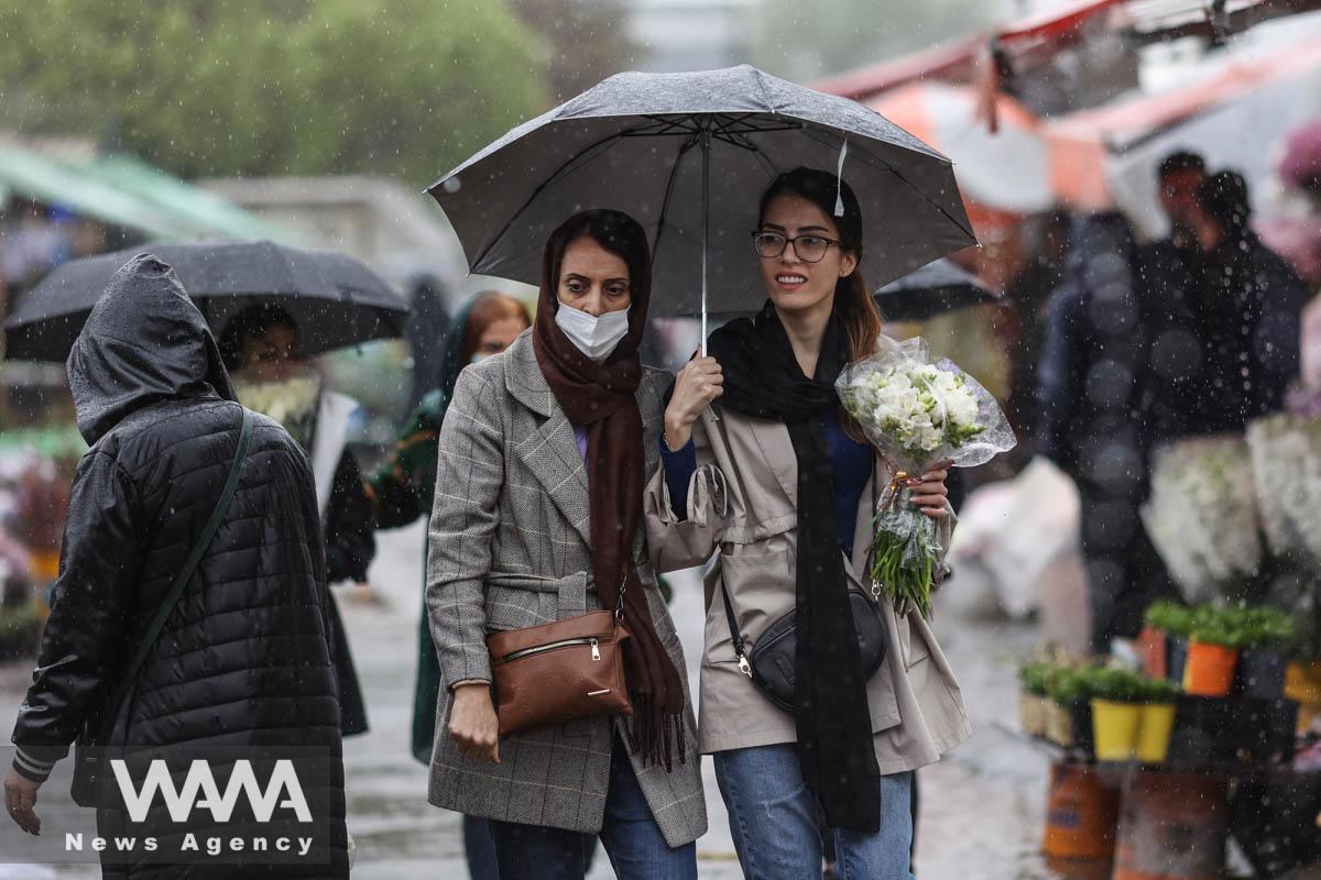 Iranian women walk through rain in a flower market, ahead of Nowruz, the Iranian New Year, in Tehran, Iran March 16, 2023. Majid Asgaripour/WANA (West Asia News Agency)