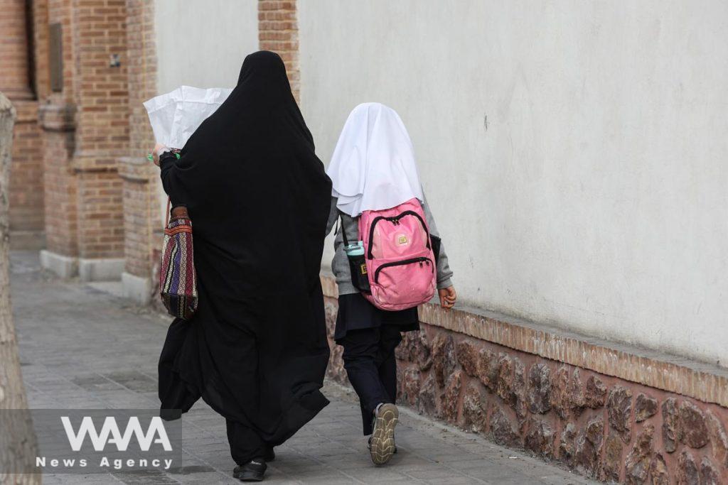 An Iranian woman walks with her student daughter in a street in Tehran, Iran, March 7, 2023. Majid Asgaripour/WANA (West Asia News Agency)