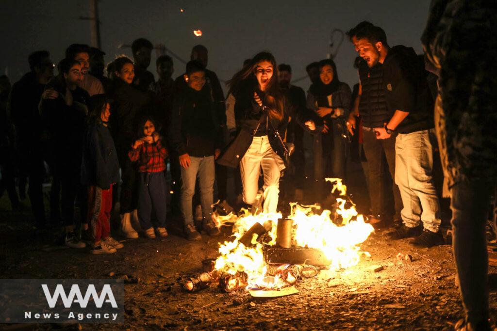 An Iranian woman jumps over a fire during the Wednesday Fire celebration (Chahar Shanbeh Soori in Persian) in a park in Tehran, Iran March 14, 2023. Majid Asgaripour/WANA (West Asia News Agency)