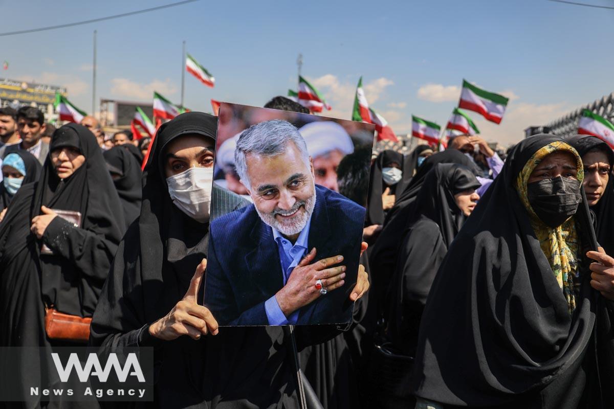 An Iranian man holds a picture of the late Iranian Major-General Qassem Soleimani, during the funeral ceremony of Milad Heydari and Meghdad Mahghani, members of Iran's Islamic Revolution Guards Corps (IRGC) who were killed in an Israeli airstrike on Damascus, held in Tehran, Iran, April 4, 2023. Majid Asgaripour/WANA (West Asia News Agency)