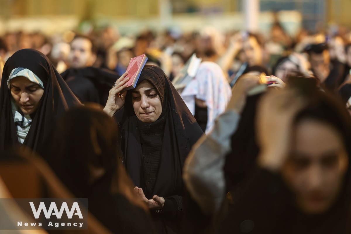 An Iranian Shia Muslim woman puts a copy of the Quran on her head while marking the death anniversary of Imam Ali, during the holy month of Ramadan, at the shrine of Abdol-Azim in Tehran, Iran, April 12, 2023. Majid Asgaripour/WANA (West Asia News Agency)