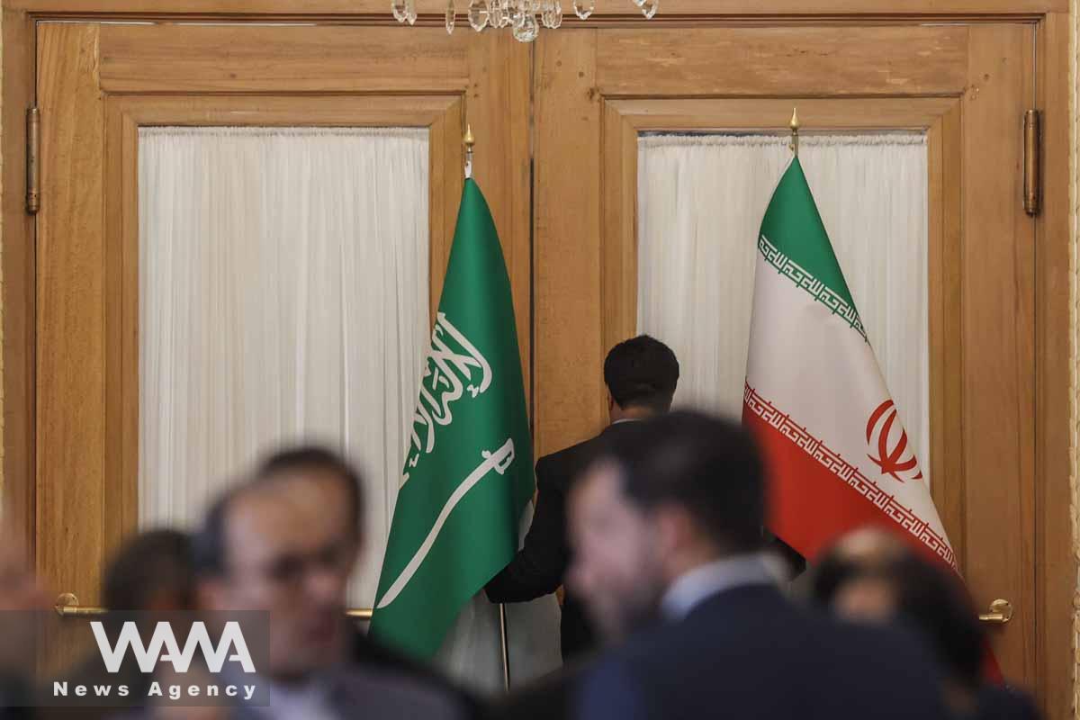 An Iranian Foreign Ministry employee carries the flags of Iran and Saudi Arabia before a news conference between Iranian Foreign Minister Hossein Amir-Abdollahian and Saudi Arabia's Foreign Minister Prince Faisal bin Farhan Al Saud, in Tehran, Iran June 17, 2023. Majid Asgaripour/WANA (West Asia News Agency)