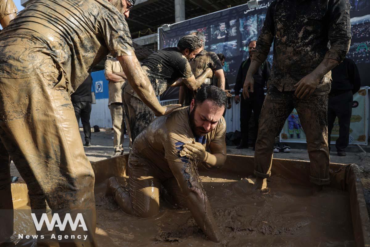 An Iranian Shi'ite Muslim immerses himself in mud during a ceremony to mark Ashura, the holiest day on the Shi'ite Muslim calendar, in Tehran, Iran July 28, 2023. Majid Asgaripour/WANA (West Asia News Agency)