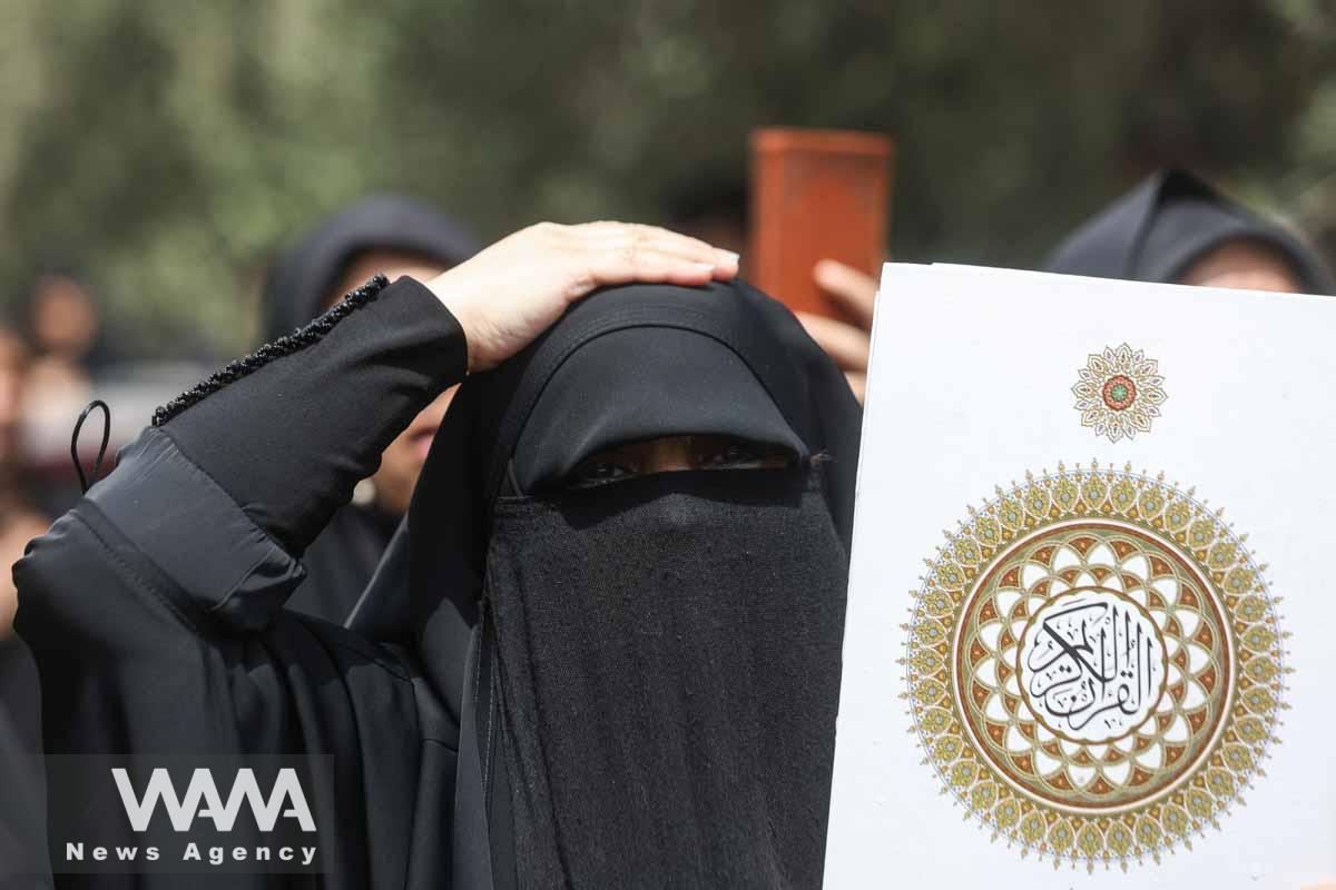 An Iranian protester holds the Koran in her hand, during a protest against the insult to the Koran in Stockholm, in Tehran, Iran July 21, 2023. Majid Asgaripour/WANA (West Asia News Agency)