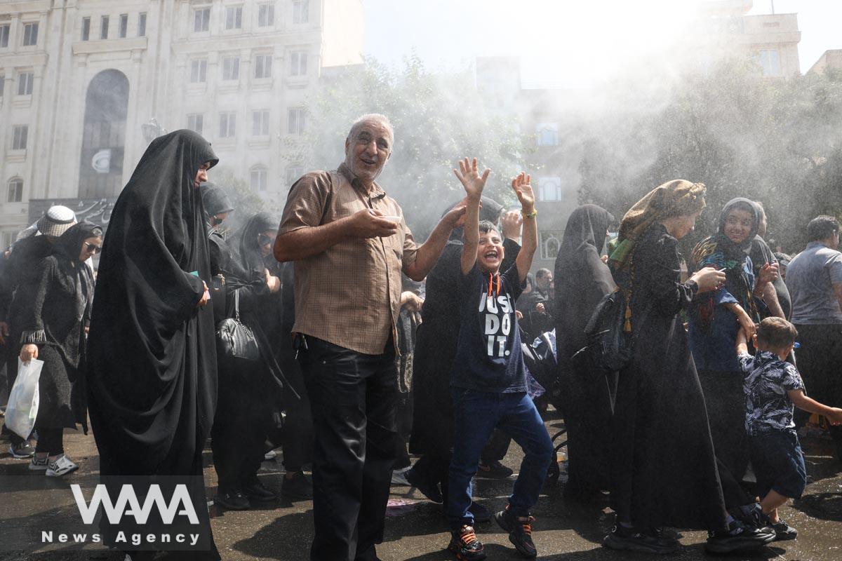 Iranian people walk as they commemorate Arbaeen and cool off under water sprinklers, in southern Tehran, Iran September 6, 2023. Majid Asgaripour/WANA (West Asia News Agency)
