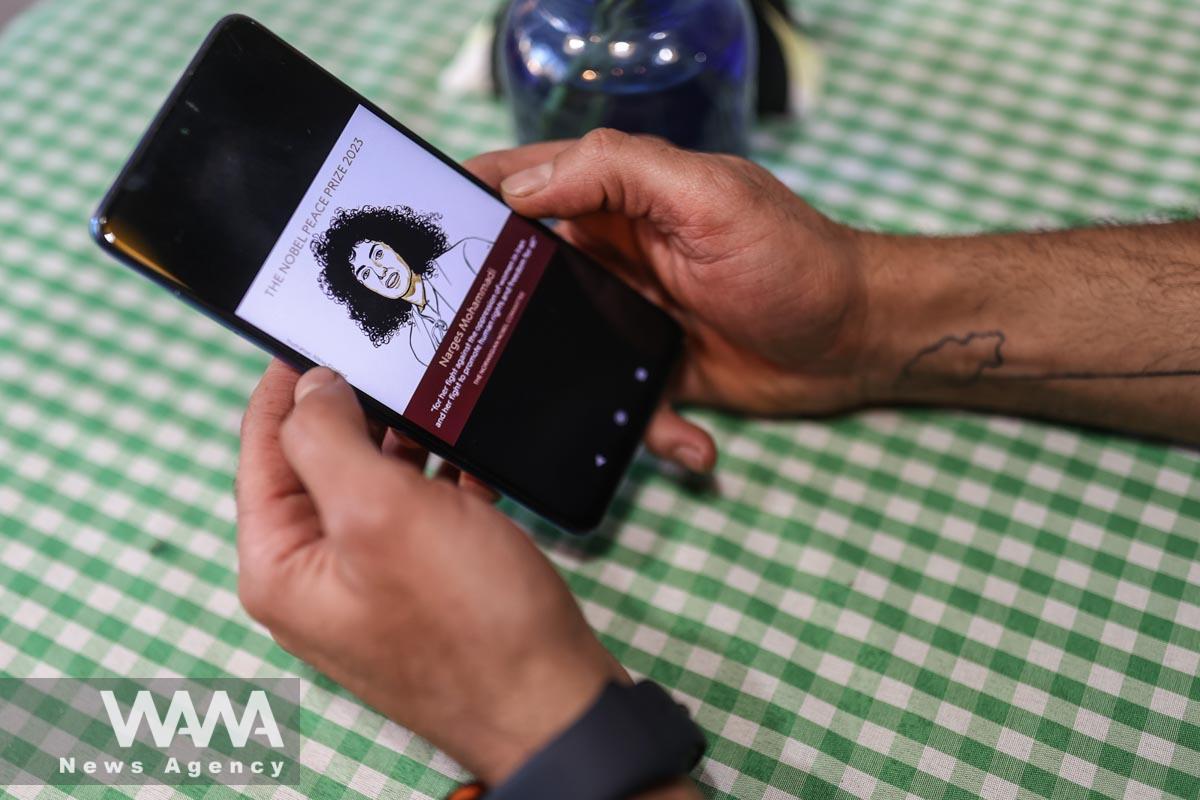 An Iranian man sees the news of Iranian activist Narges Mohammadi winning the Nobel Peace Prize on his mobile phone, in a cafe in Tehran, Iran, October 6, 2023. Majid Asgaripour/WANA (West Asia News Agency)