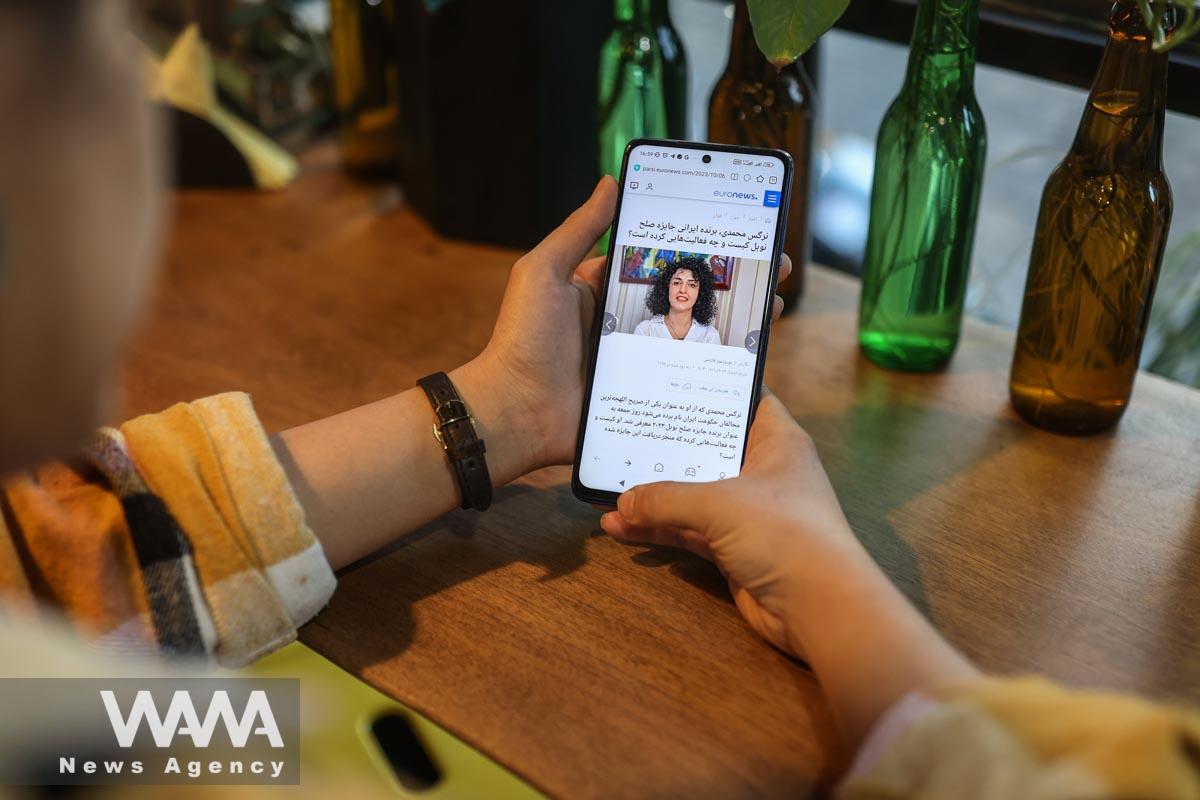 An Iranian woman sees the news of Iranian activist Narges Mohammadi winning the Nobel Peace Prize on her mobile phone, in a cafe in Tehran, Iran, October 6, 2023. Majid Asgaripour/WANA (West Asia News Agency)