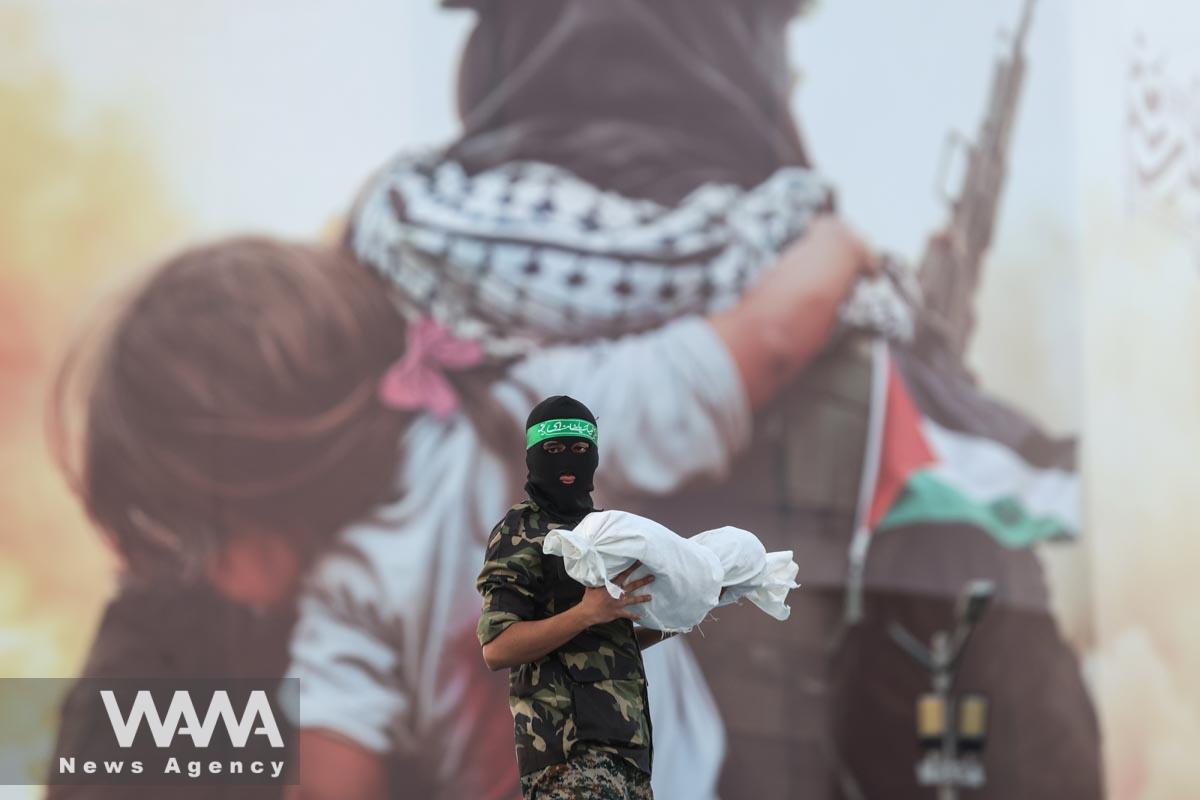 A member of Basij paramilitary forces holds a symbolic shroud of Gaza children's dead bodies during an anti-Israel protest in Tehran/WANA (West Asia News Agency)
