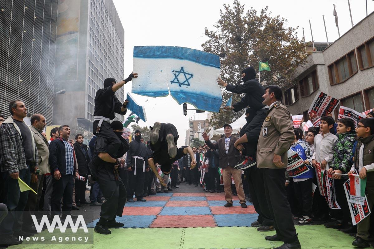 An Iranian man kicks a plastic Israeli flag during the 44th anniversary of the U.S. expulsion from Iran/WANA (West Asia News Agency)