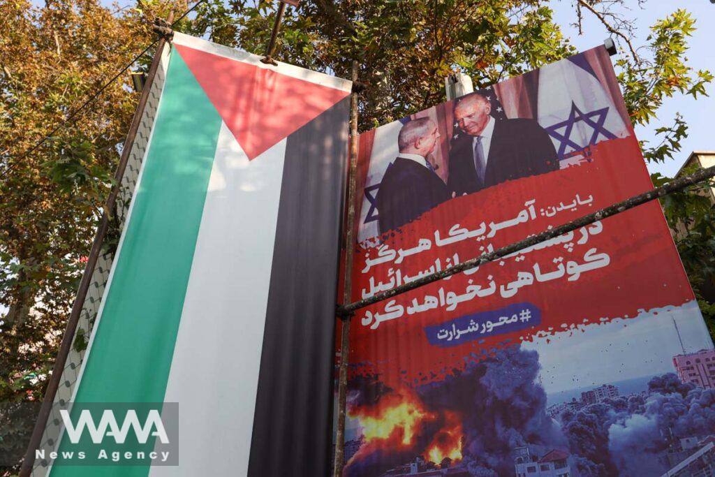 A banner with a photo of U.S. President Joe Biden and Israeli Prime Minister Benjamin Netanyahu is seen next to the Palestinian flag in a street in Iran/WANA (West Asia News Agency)