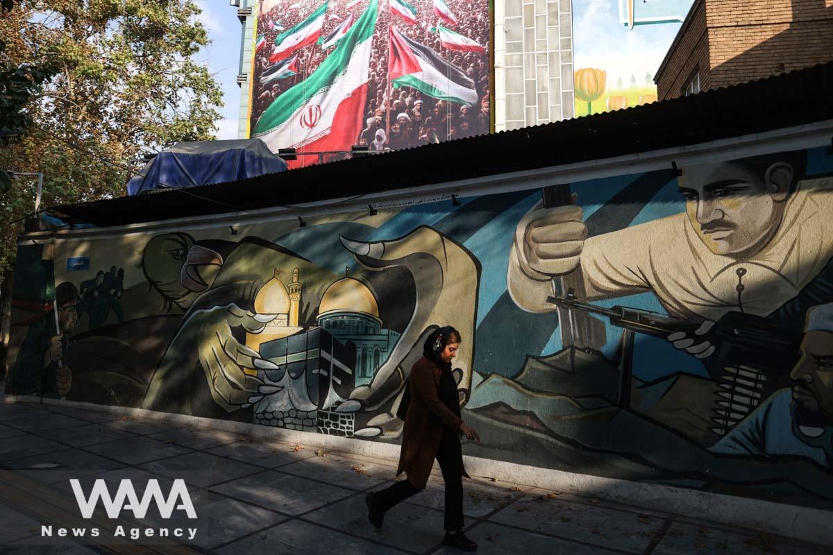 An Iranian woman walks past A pro-Palestine mural in a street in Iran/WANA (West Asia News Agency)