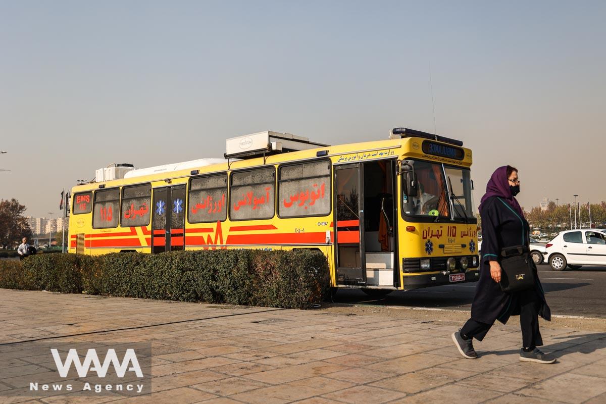 An Iranian woman walks next to an ambulance bus following the increase in air pollution in Tehran