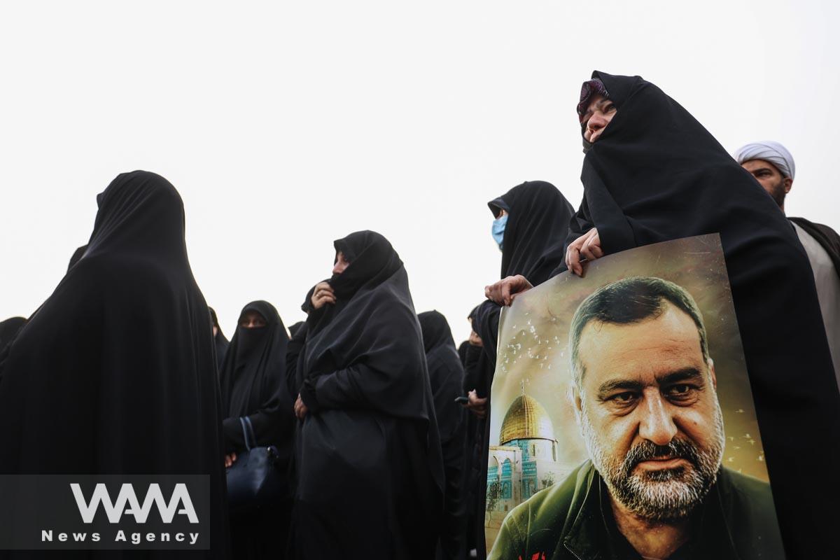 An Iranian woman holds a picture of senior adviser for Iran's Revolutionary Guards, Sayyed Razi Mousavi, who was killed in an Israeli air strike outside the Syrian capital Damascus, during his funeral