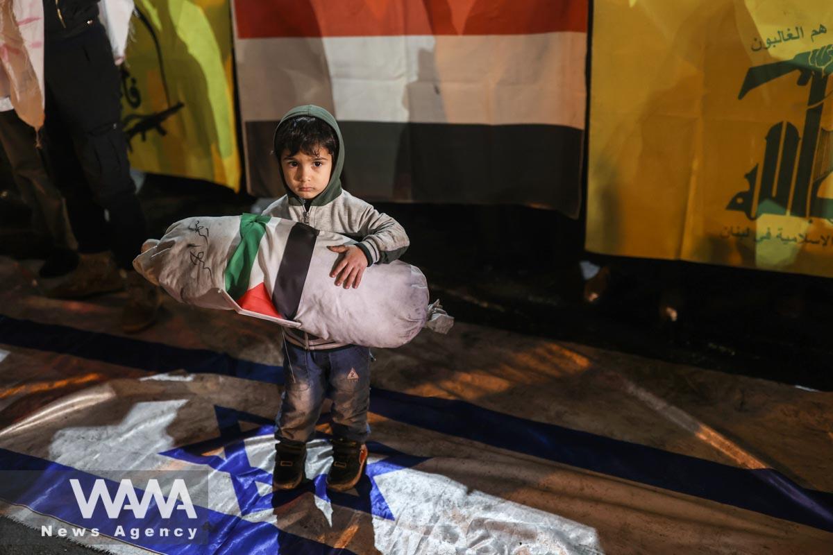 An Iranian child stans on the Israeli flag during a gathering in support of Yemen in front of the British embassy in Iran/WANA (West Asia News Agency)