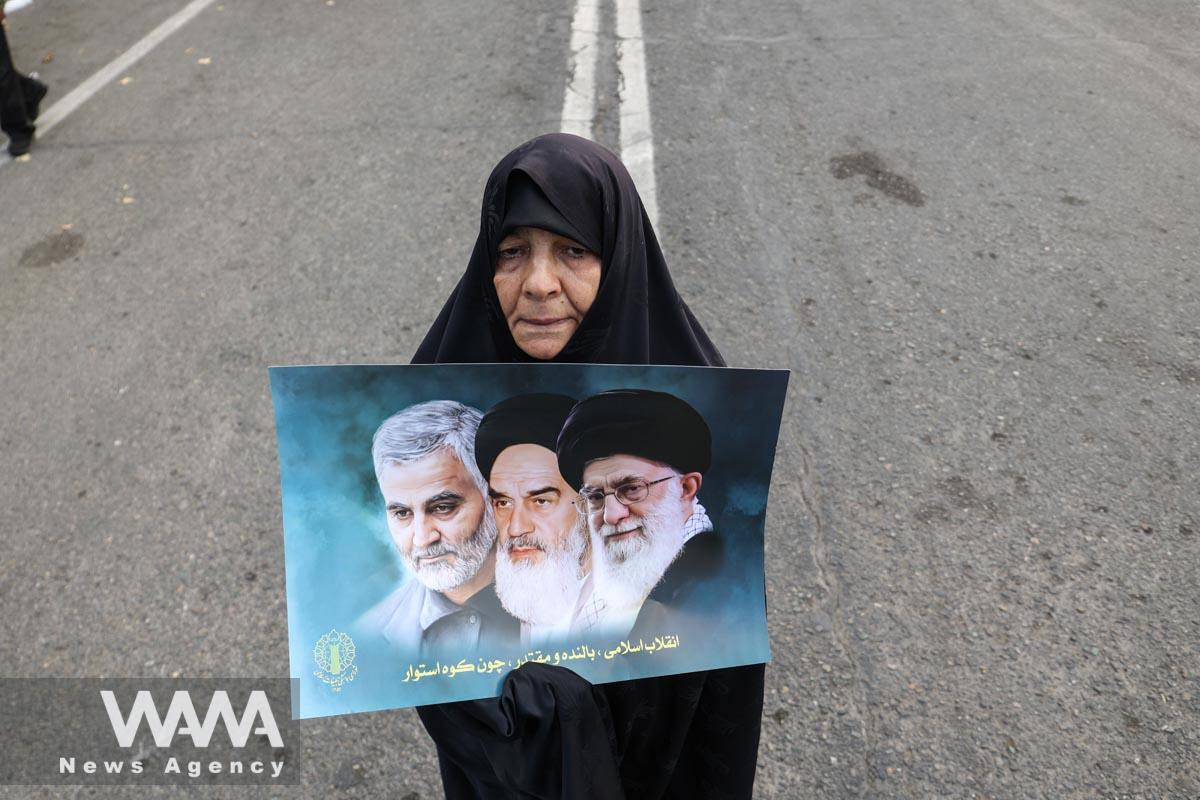 An Iranian woman holds a picture of Ayatollah Ali Khamenei and Iran's late leader Ayatollah Ruhollah Khomeini, during the funeral ceremony of Faezeh Rahimi one of the casualties of the ISIS attack in Kerman, after Friday prayers