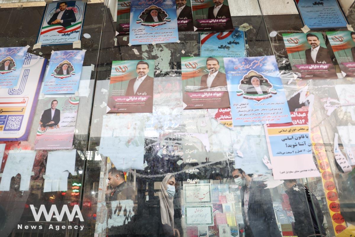 People walk past campaign posters for the parliamentary election