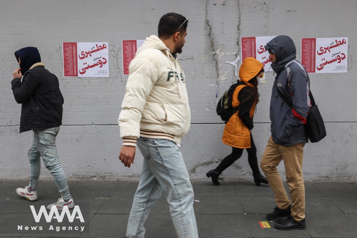 People walk past campaign posters for the parliamentary election during the last day of election campaigning