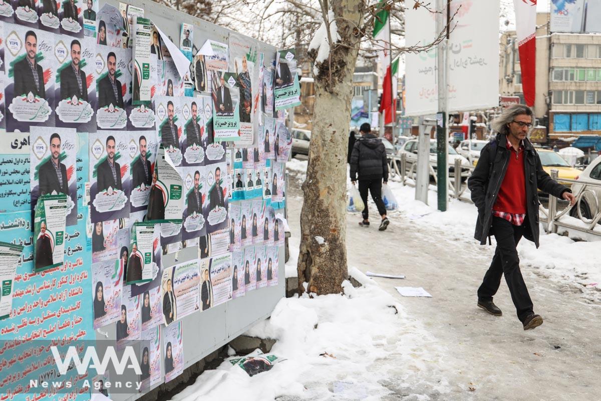 People walk past campaign posters for the parliamentary election during the last day of election campaigning