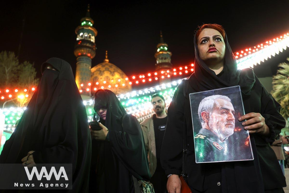 An Iranian woman holds a picture of Qassem Soleimani during an anti-Israel protest