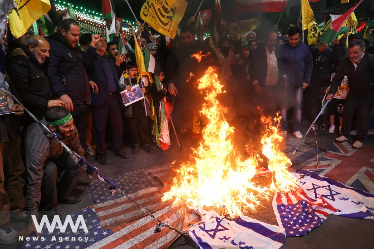 Protesters burn the U.S. flag and the Israeli flag during an anti-Israel protest
