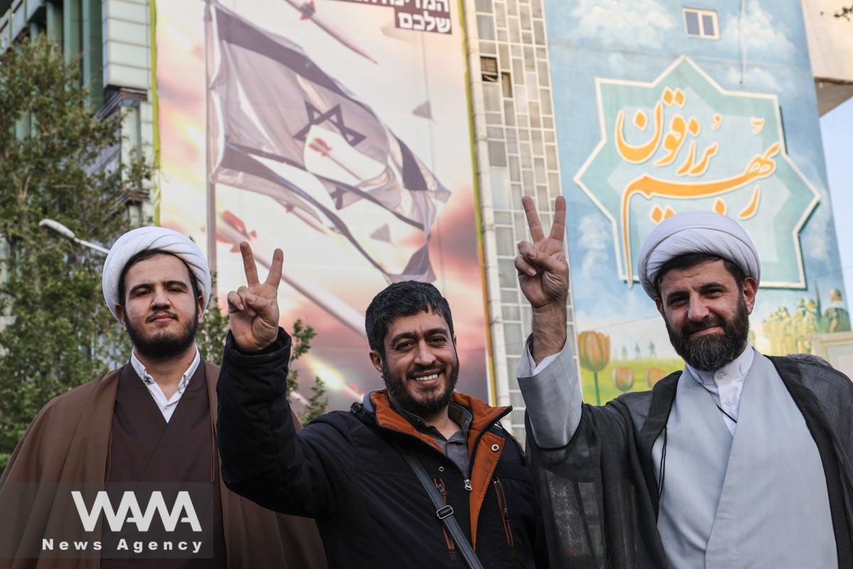 An Iranian cleric shows victory next to an anti-Israel billboard during a celebration following the IRGC attack on Israel