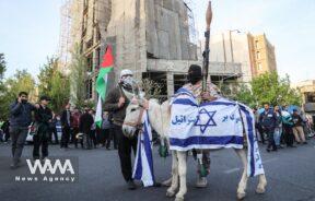 An anti-Israel billboard is seen next to the Iranian flag during a celebration following the IRGC attack on Israel