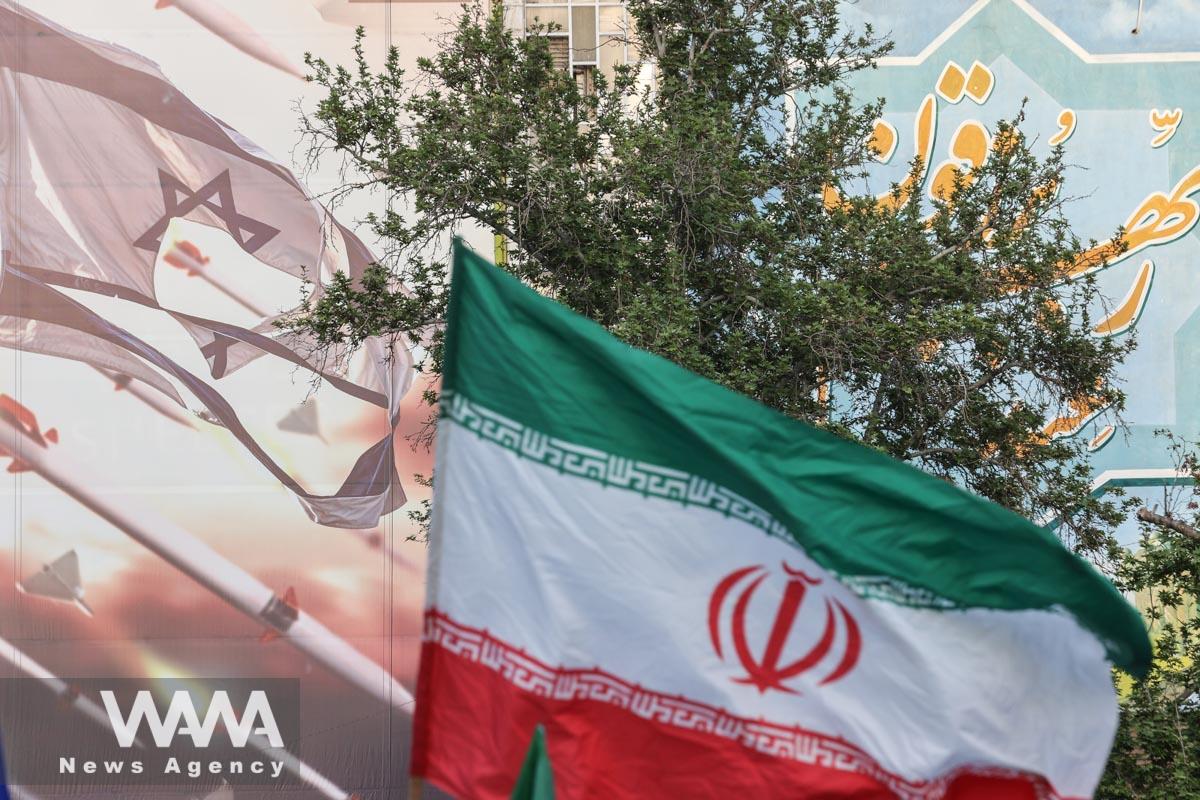 An anti-Israel billboard is seen next to the Iranian flag during a celebration following the IRGC attack on Israel