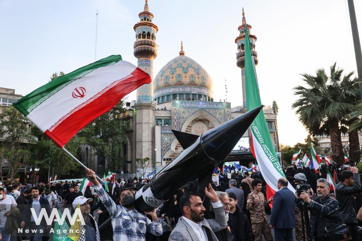 Iranians carry a model of a missile during a celebration following the IRGC attack on Israel