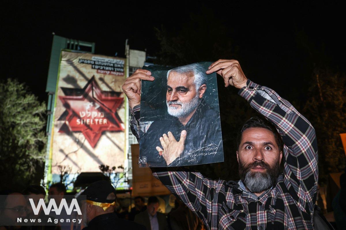 An Iranian man holds a poster of senior Iranian military commander General Qassem Soleimani during a celebration after the IRGC attack on Israel