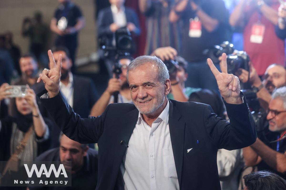 Presidential candidate Masoud Pezeshkian shows the victory sign during a campaign event