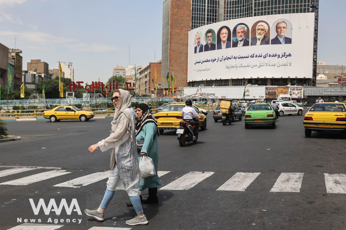 People walk past a billboard with a picture of the presidential candidates on a street