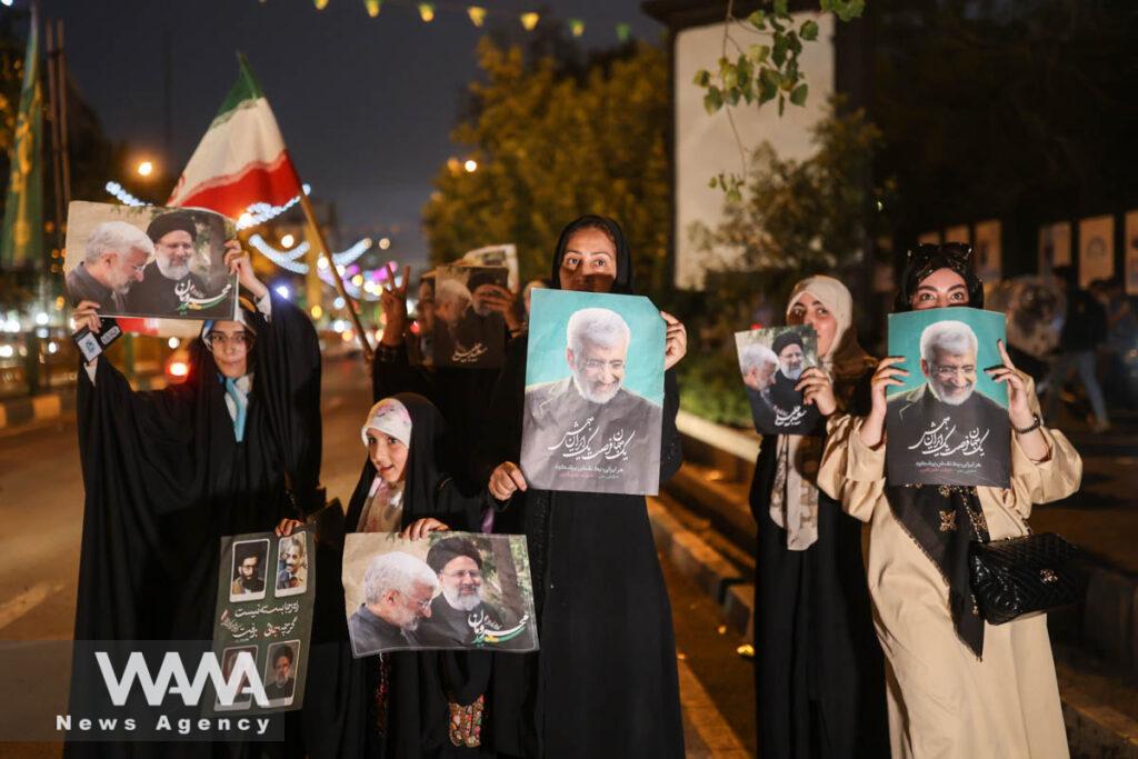 Supporters of Iranian presidential candidate Saeed Jalili hold posters of him on a street in Tehran