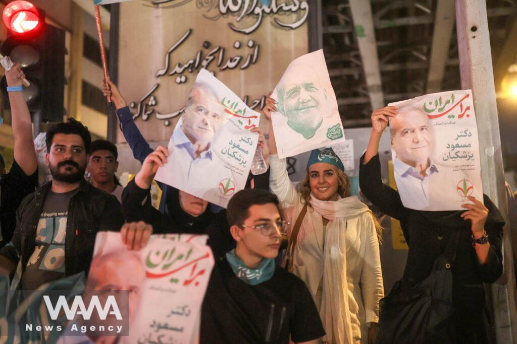 Supporters hold posters of Iranian presidential candidate Masoud Pezeshkian during a campaign event in Tehran