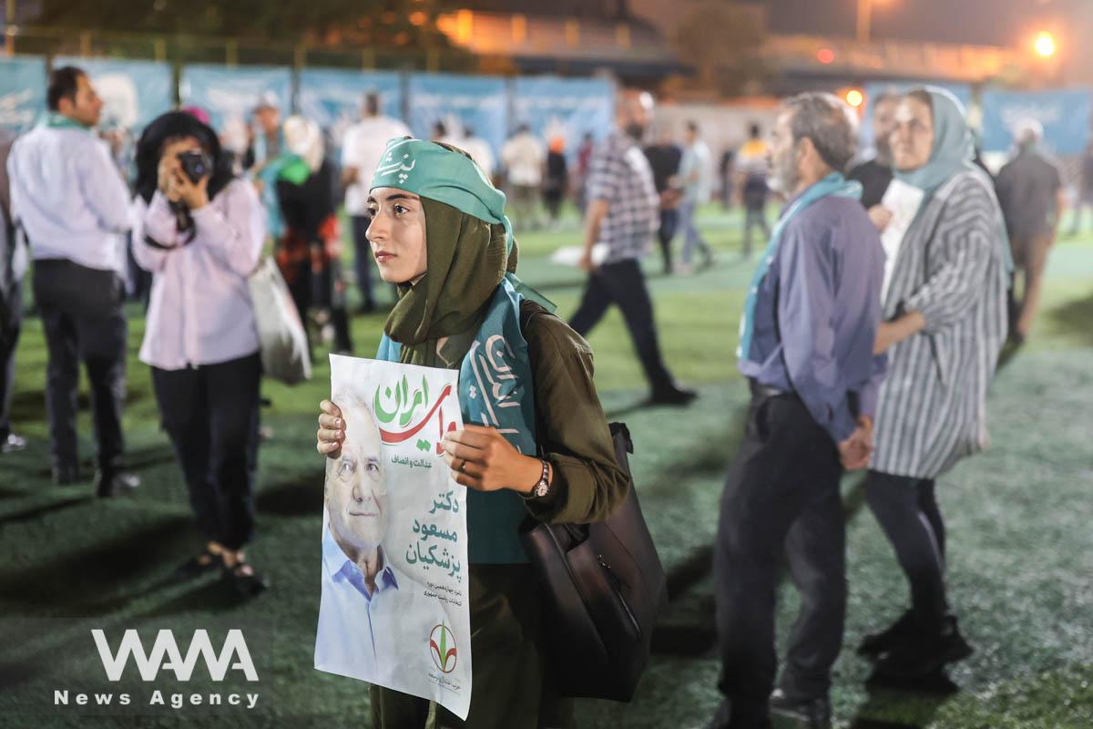 Supporters hold posters of Iranian presidential candidate Masoud Pezeshkian during a campaign event in Tehran