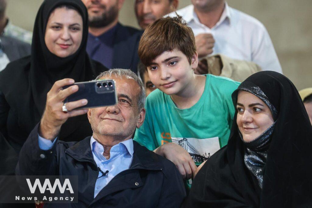 Presidential candidate Masoud Pezeshkian takes a selfie with one of his supporters during a campaign gathering