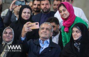 Presidential candidate Masoud Pezeshkian takes a selfie with one of his supporters during a campaign gathering