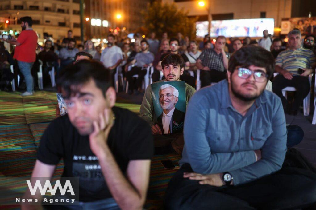 People watch the debate of presidential candidates at a park