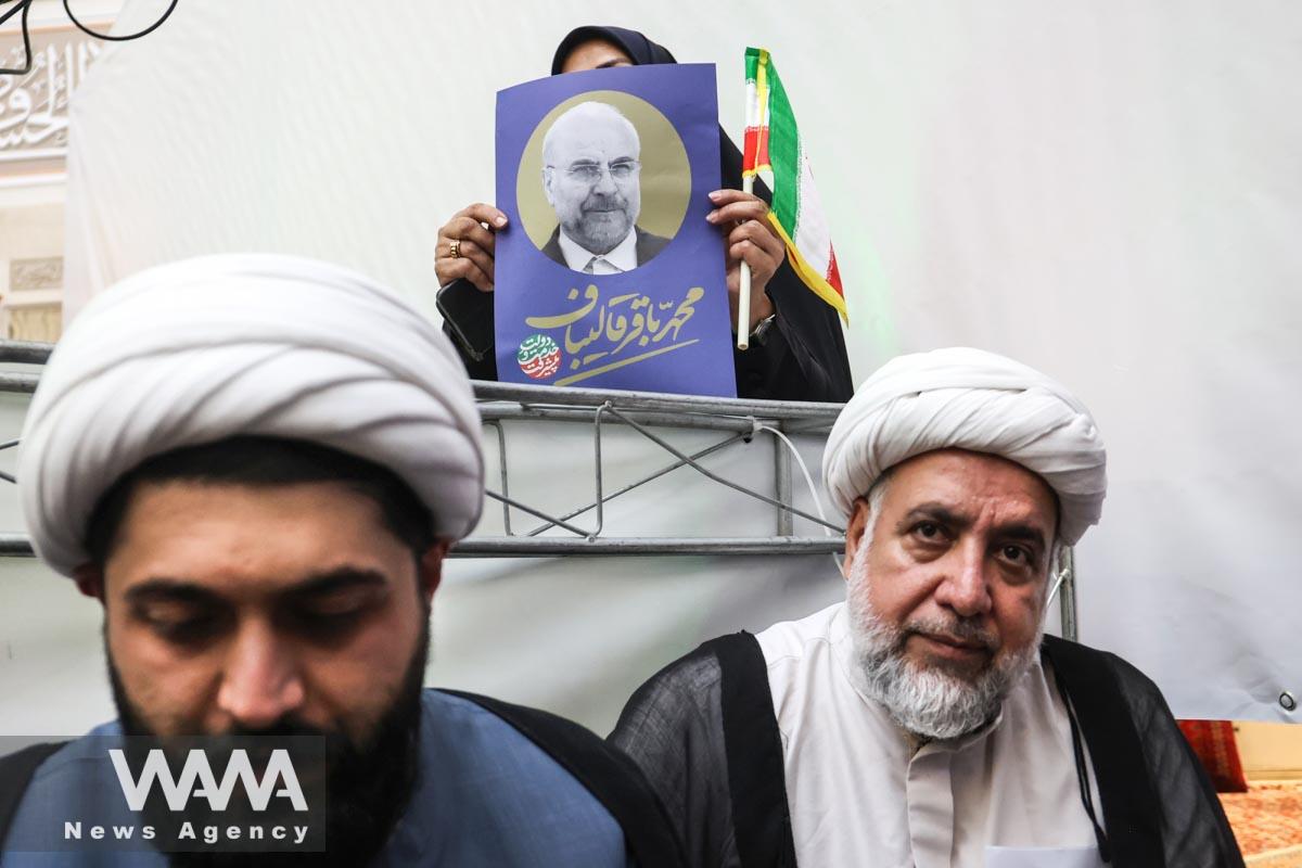 A supporter of presidential candidate Mohammad Bagher Ghalibaf holds a poster of him during a campaign event