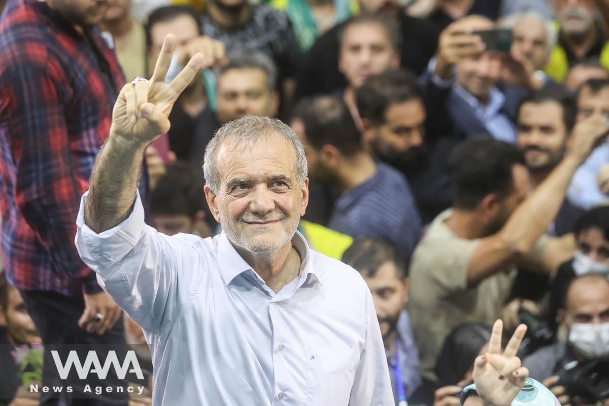 Presidential candidate Masoud Pezeshkian shows the victory sign during a campaign event