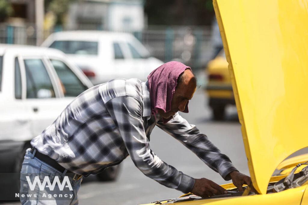 An Iranian taxi driver checks his car during the heat surge