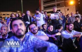 People watch the debate of presidential candidates at a park in Tehran