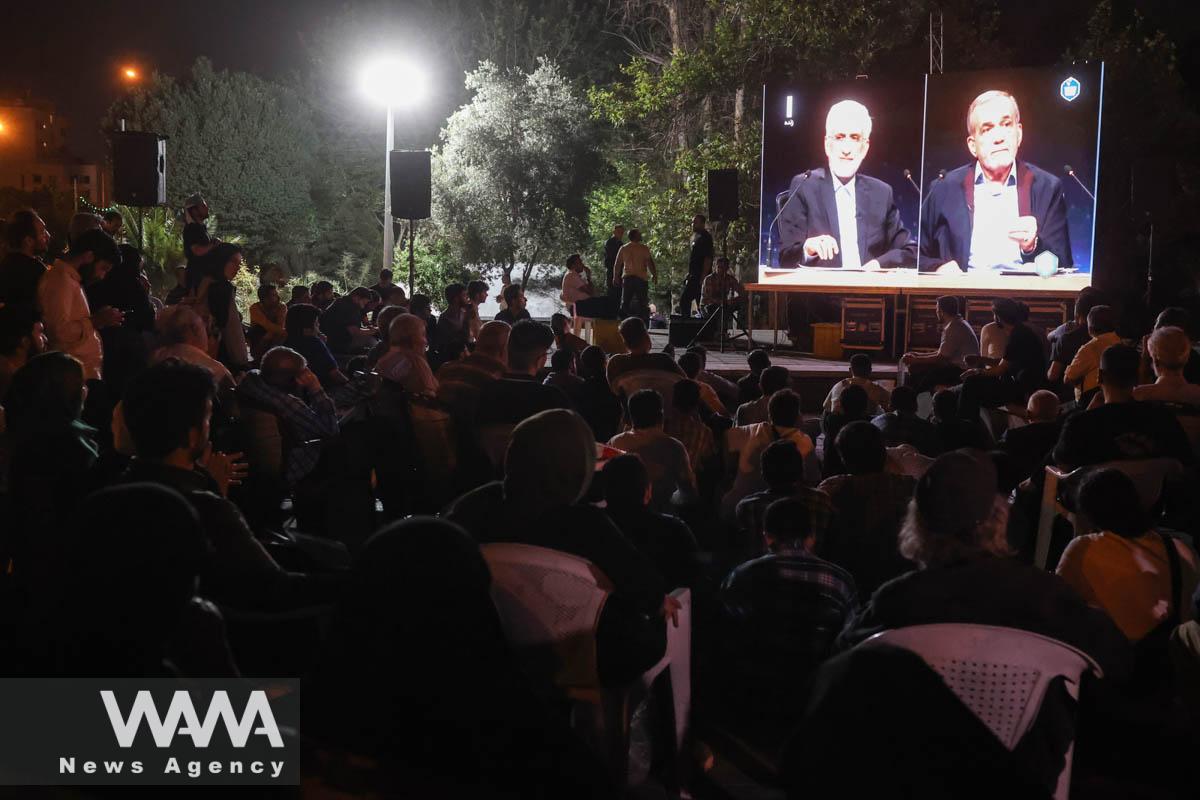 People watch the debate of presidential candidates at a park in Tehran