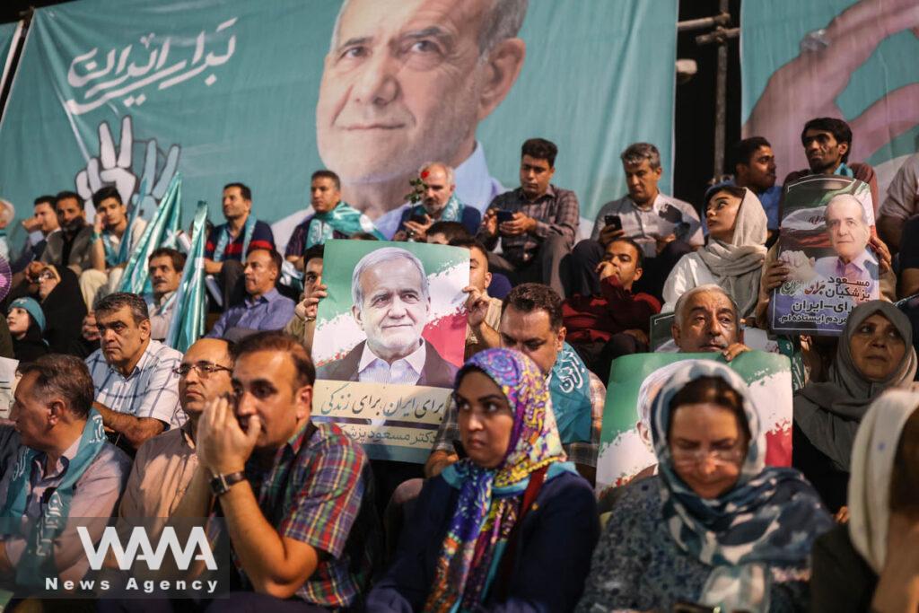 Supporters hold posters of Iranian presidential candidate Masoud Pezeshkian during a campaign event in Tehran