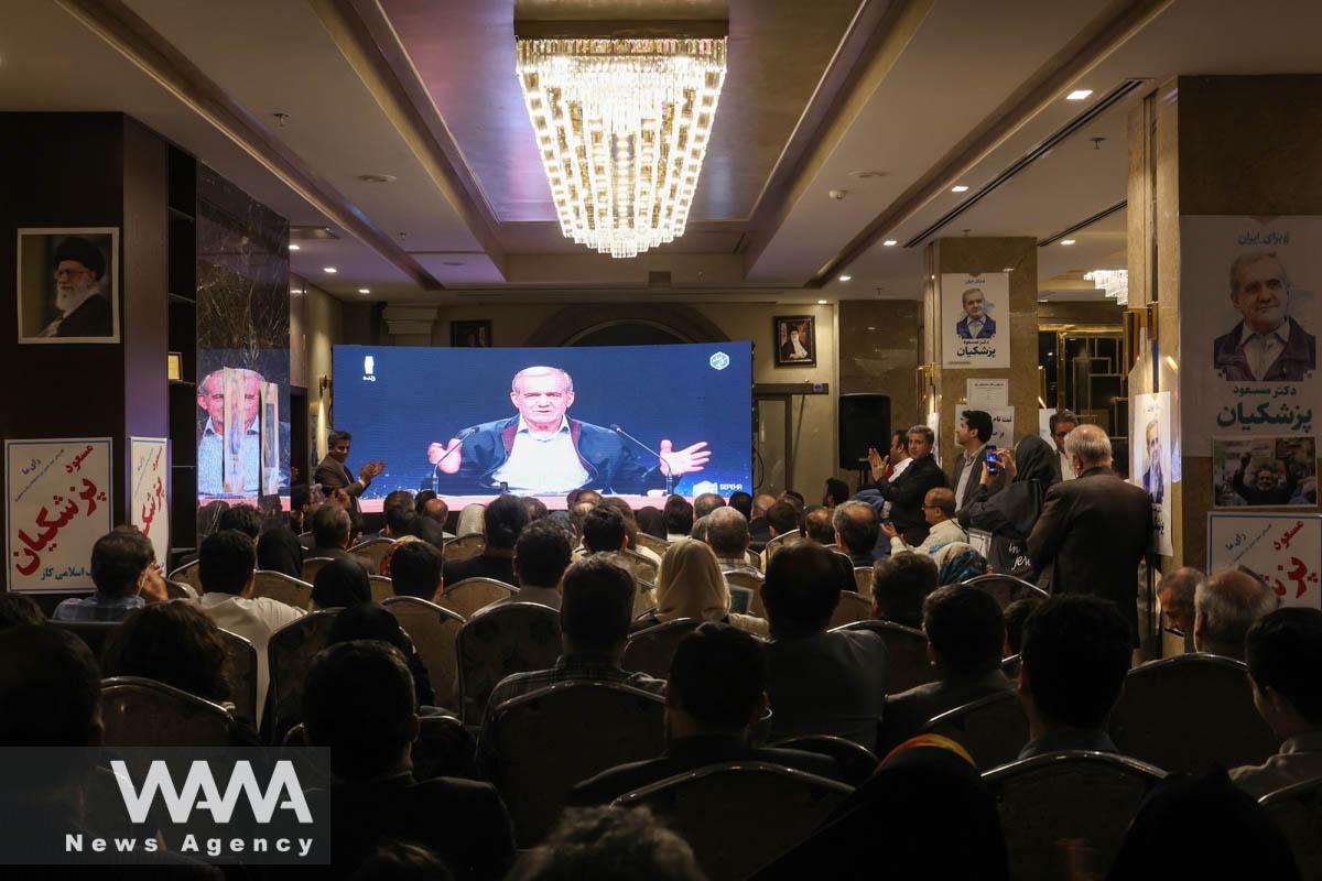 People watch the debate of presidential candidates at a campaign centre in Tehran