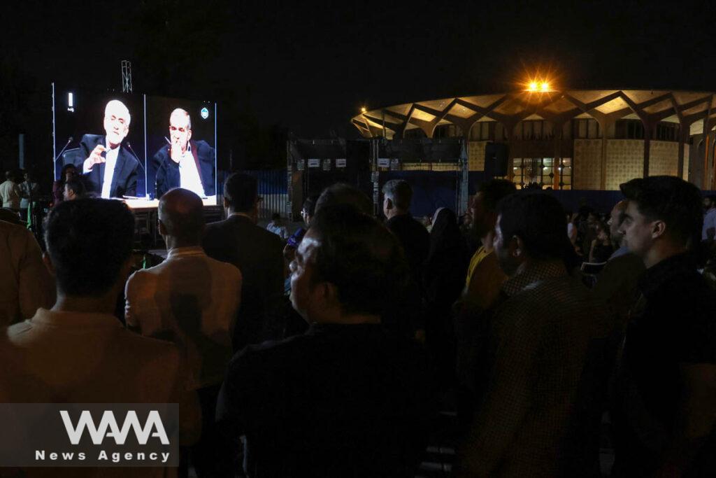 People watch the debate of presidential candidates at a park in Tehran