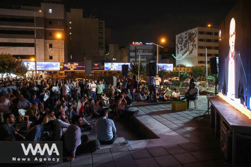 People watch the debate of presidential candidates at a park in Tehran